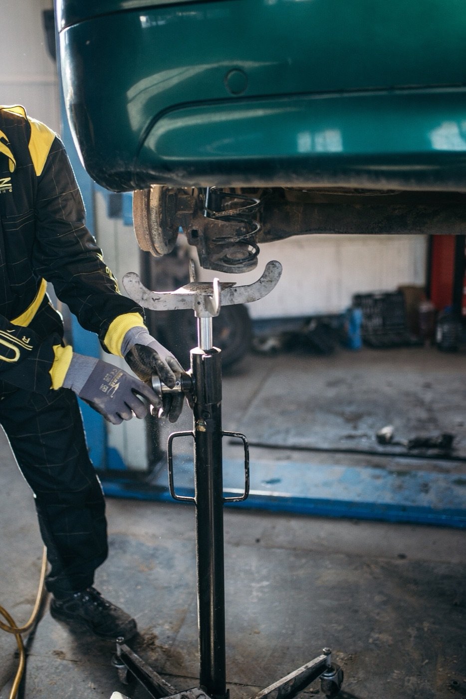 Mechanikas po pakeltu automobiliu keičia galinės važiuoklės detales